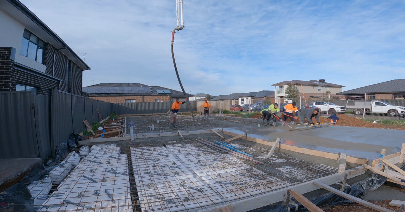 Professional crew pouring concrete slab with proper grading in Rogers, AR